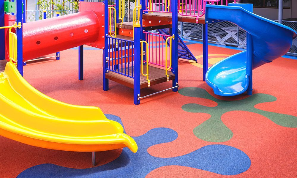 Colorful playground with slides and structures, on a red and blue surface.