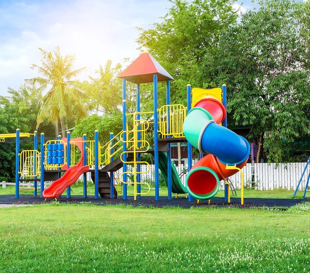 Playground with colorful slides, climbing structure, and green grass.