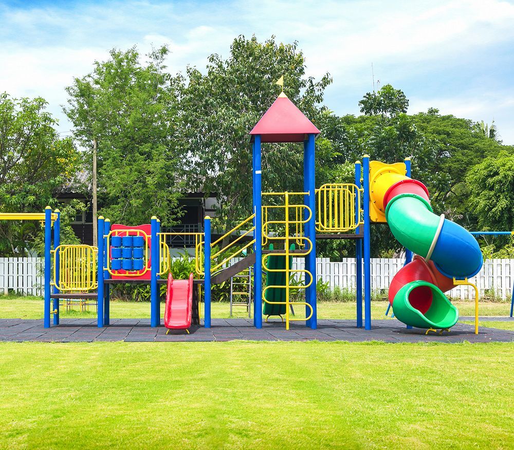 Playground with blue and yellow equipment, red slide, and green grass.