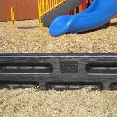 Black border around wood chips at a playground with blue slide and yellow bars in the background.
