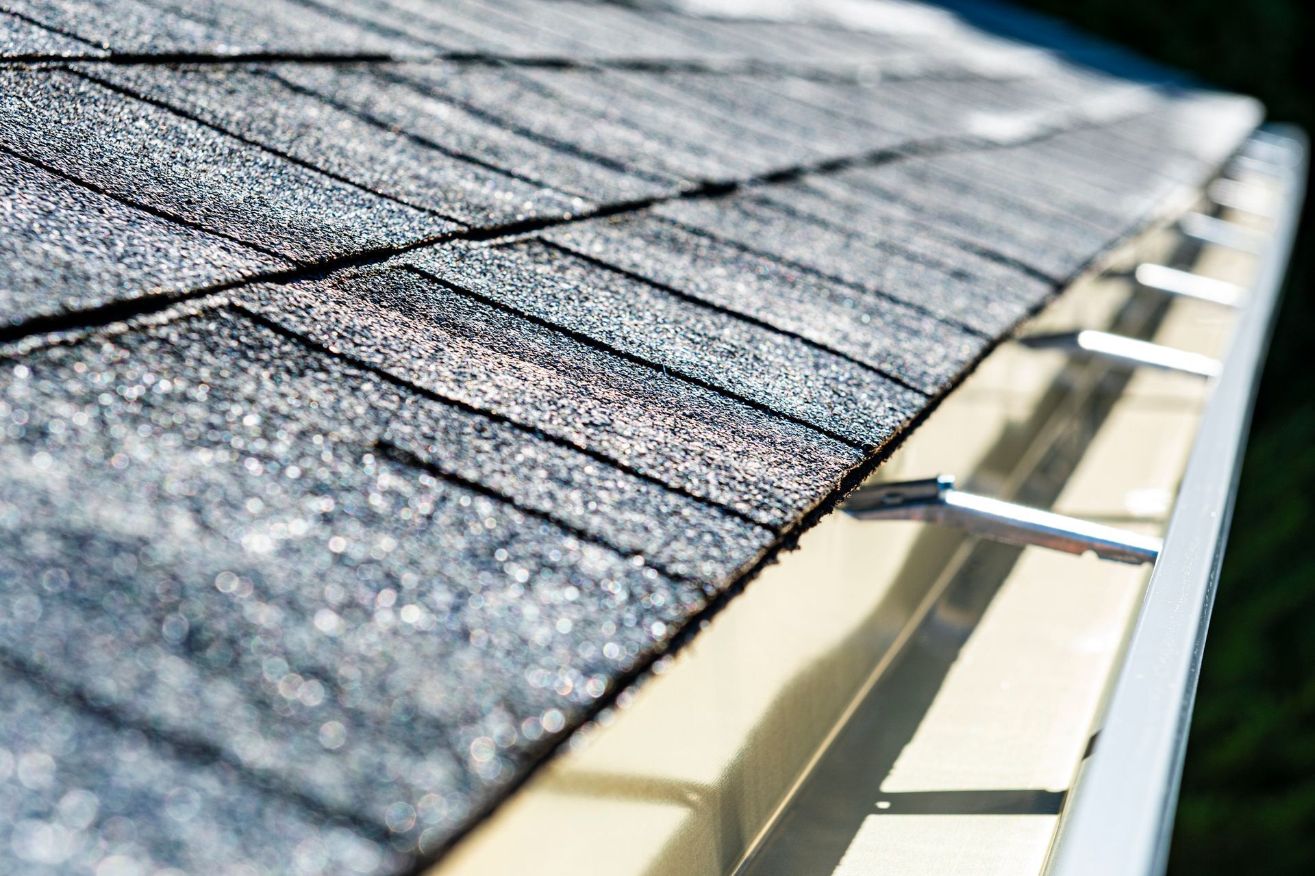 A close up of a roof with shingles and a gutter.