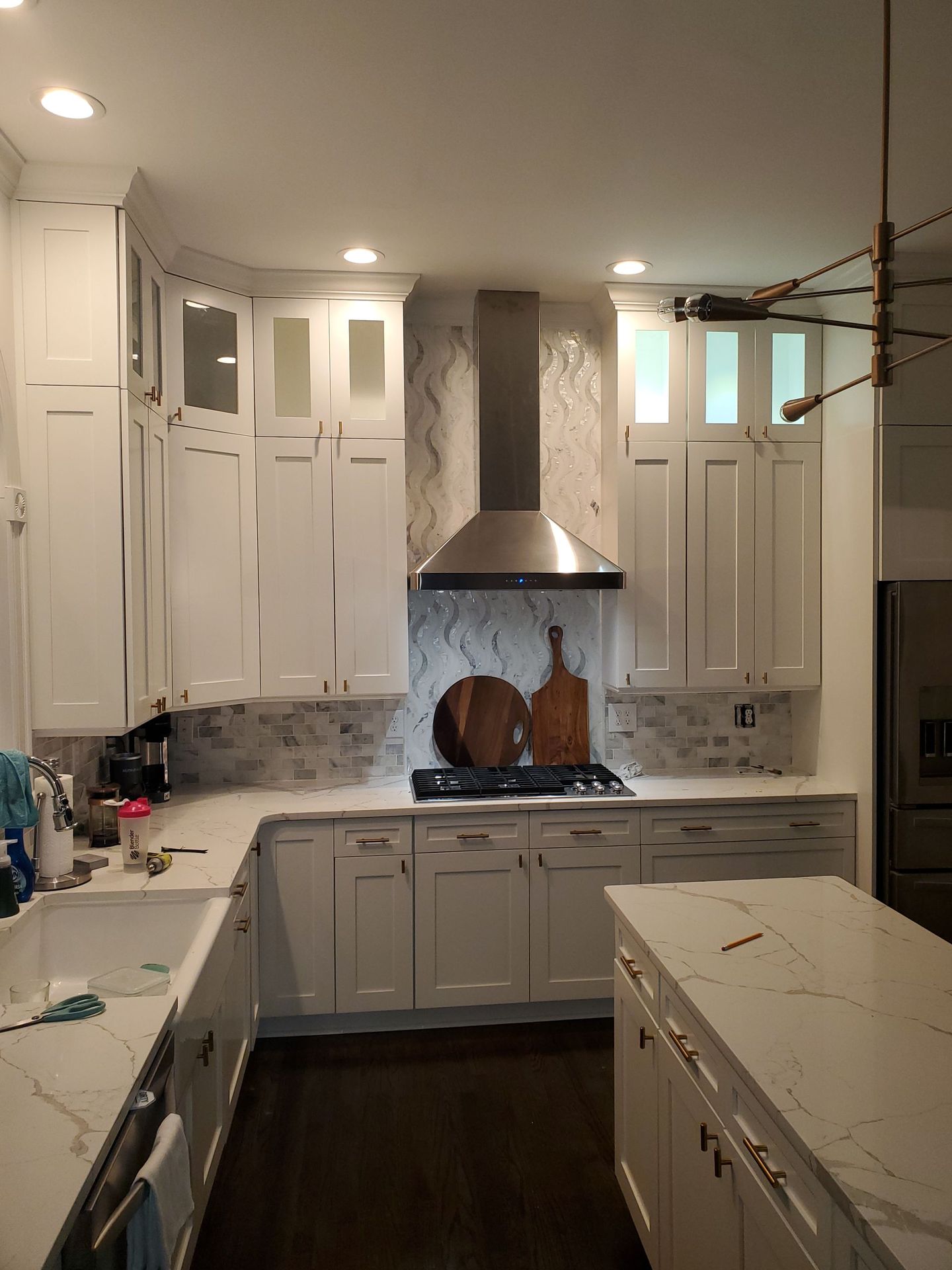 A kitchen with white cabinets , a stove , a sink , and a hood.