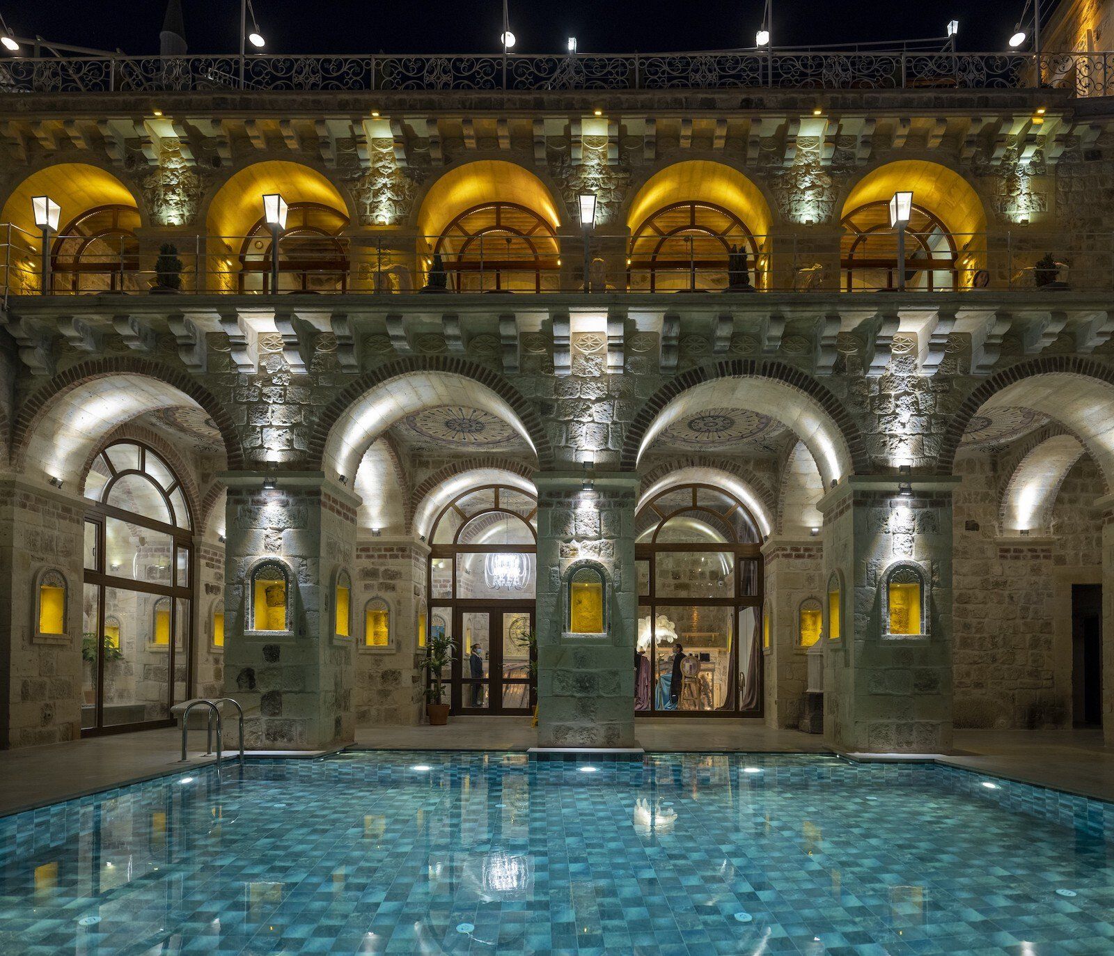 A large building with arches and a swimming pool in front of it