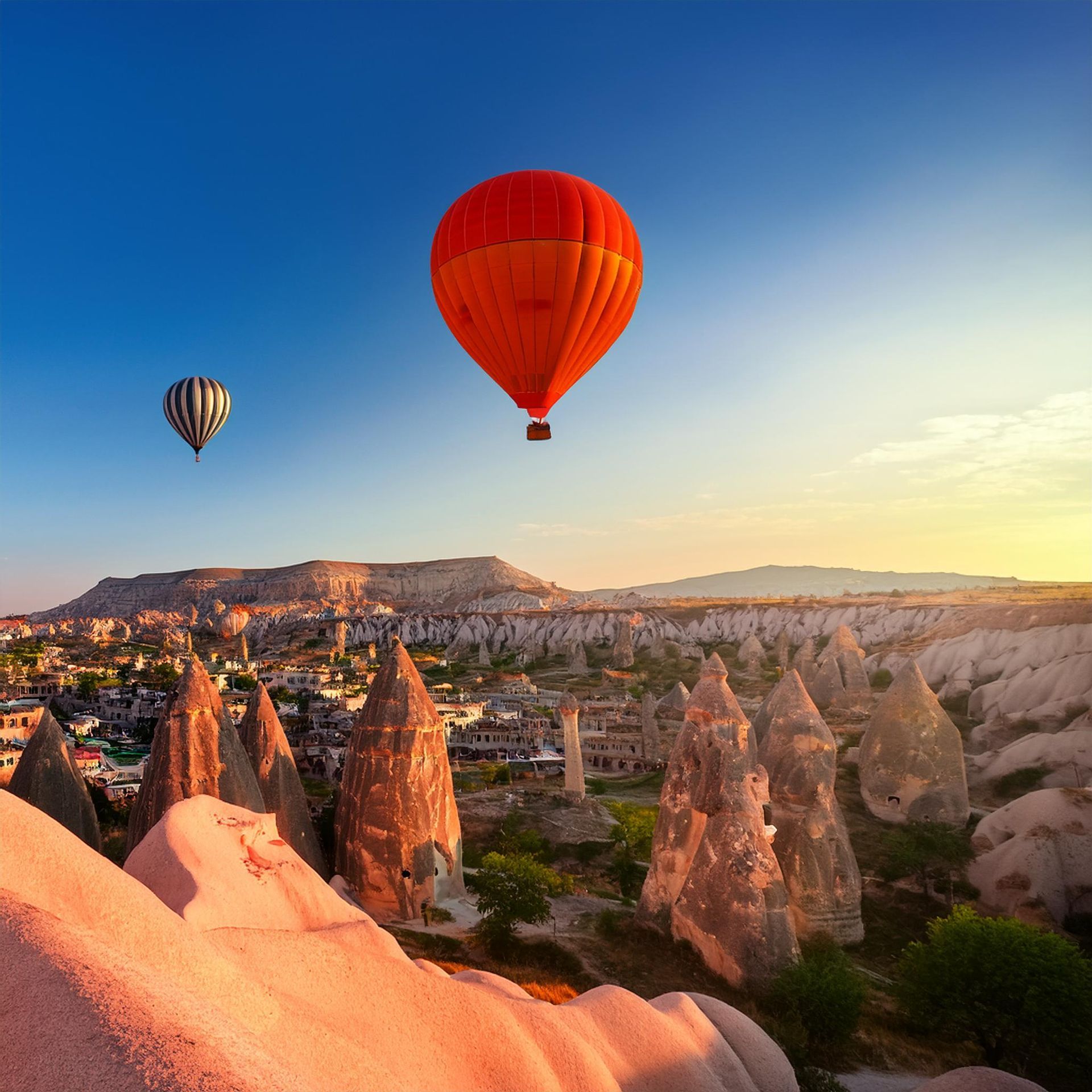 A woman in a yellow dress is hanging from a hot air balloon.