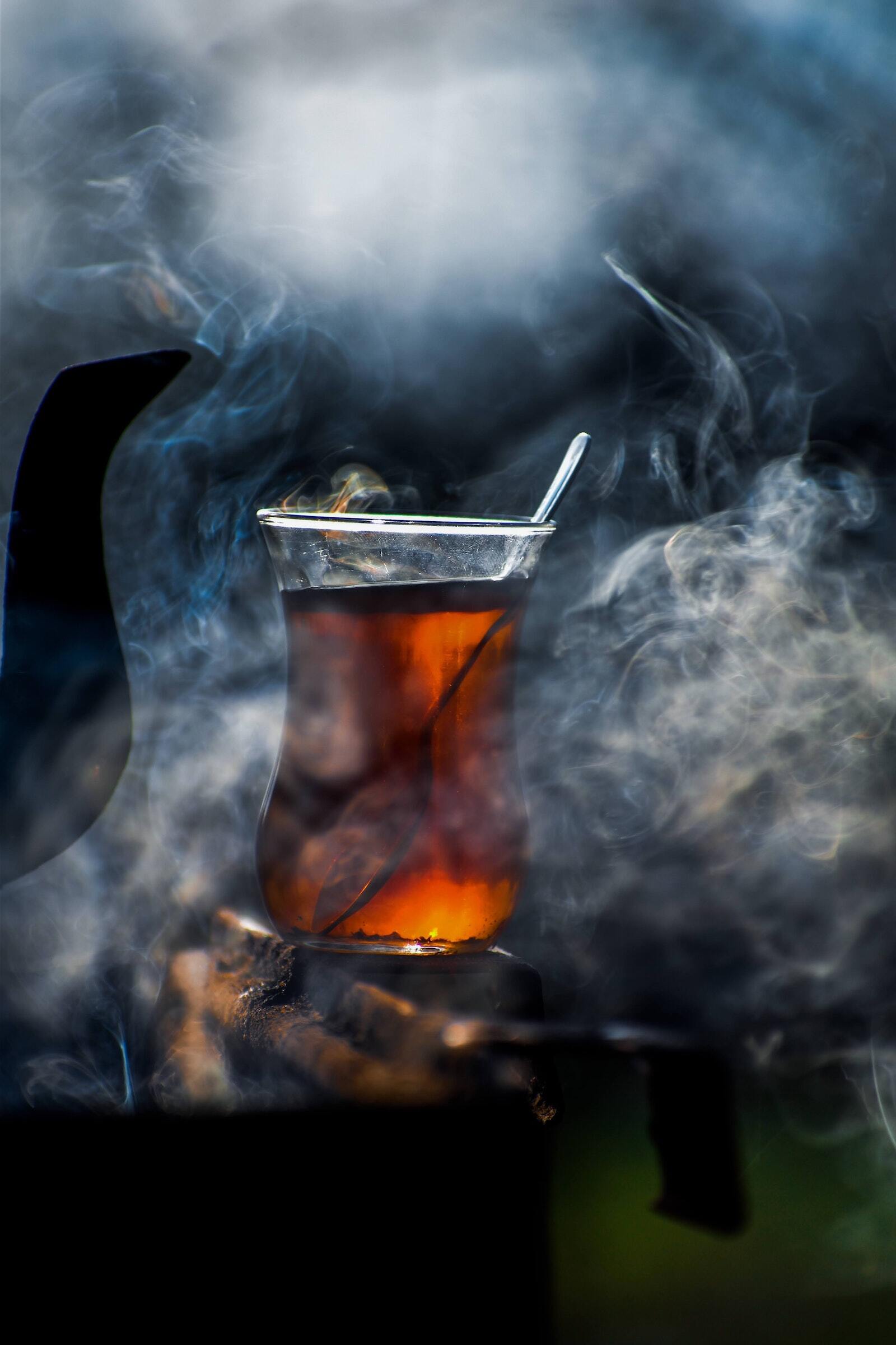 A close up of a glass of tea with smoke coming out of it.