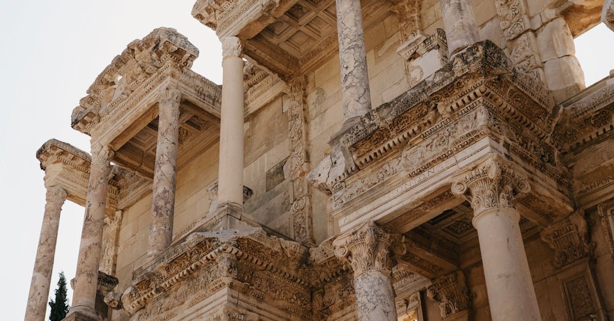 A man is walking on a rocky cliff with hot air balloons in the background.