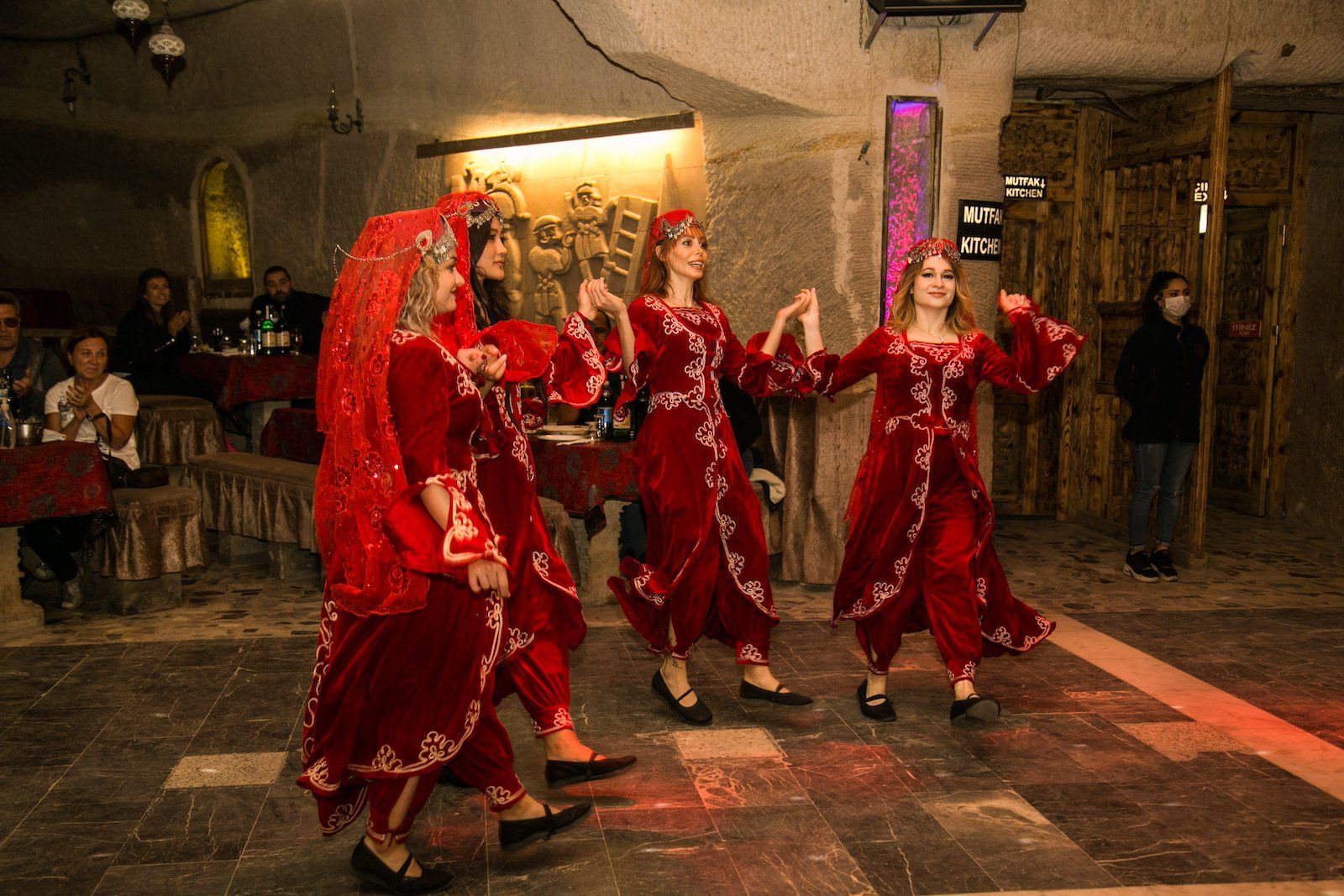 A group of women in red dresses are dancing in a room.