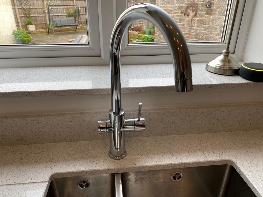 A kitchen sink with a faucet and a window in the background.