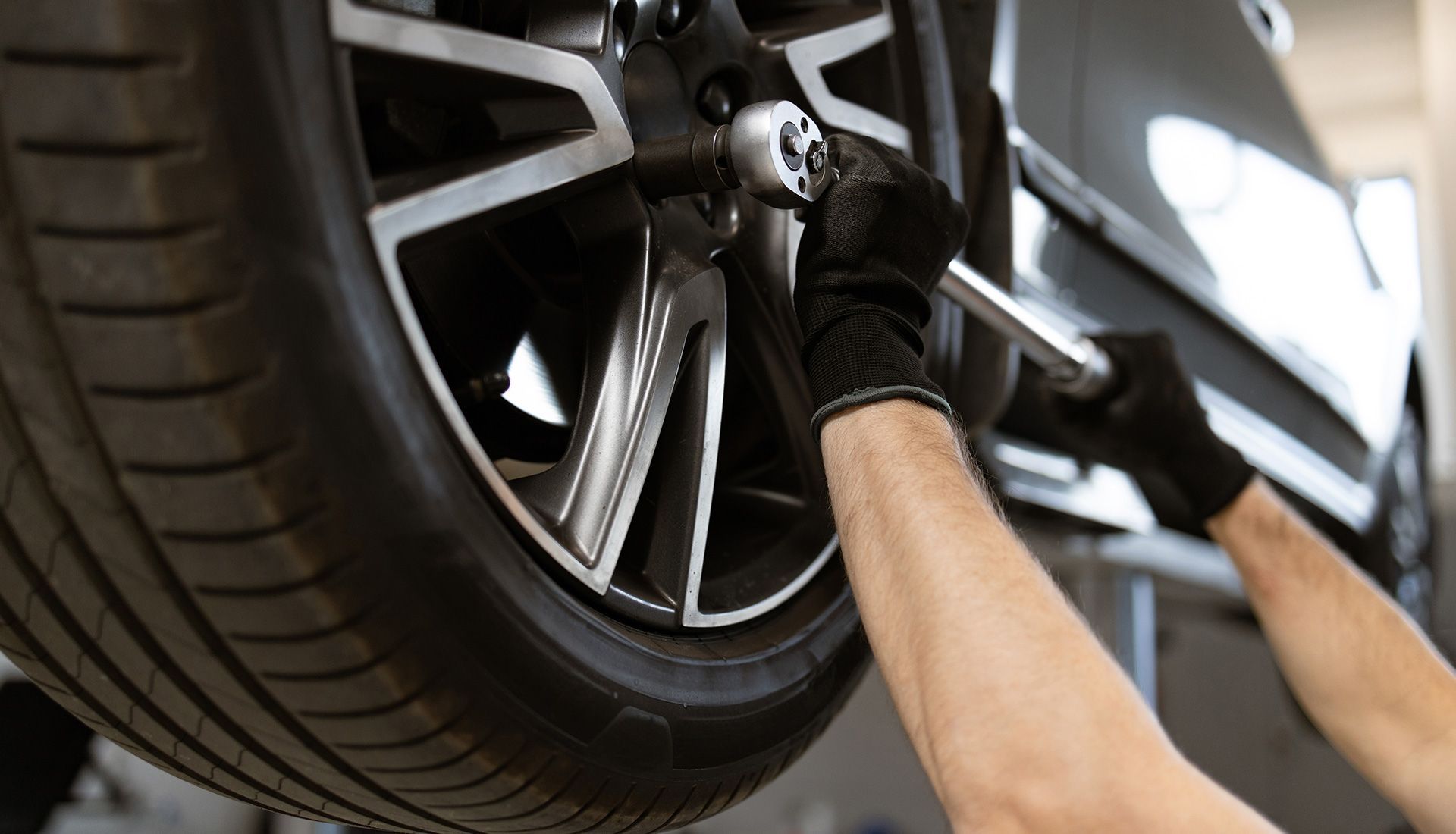 Person removing lug nuts from a car tire with a wrench.