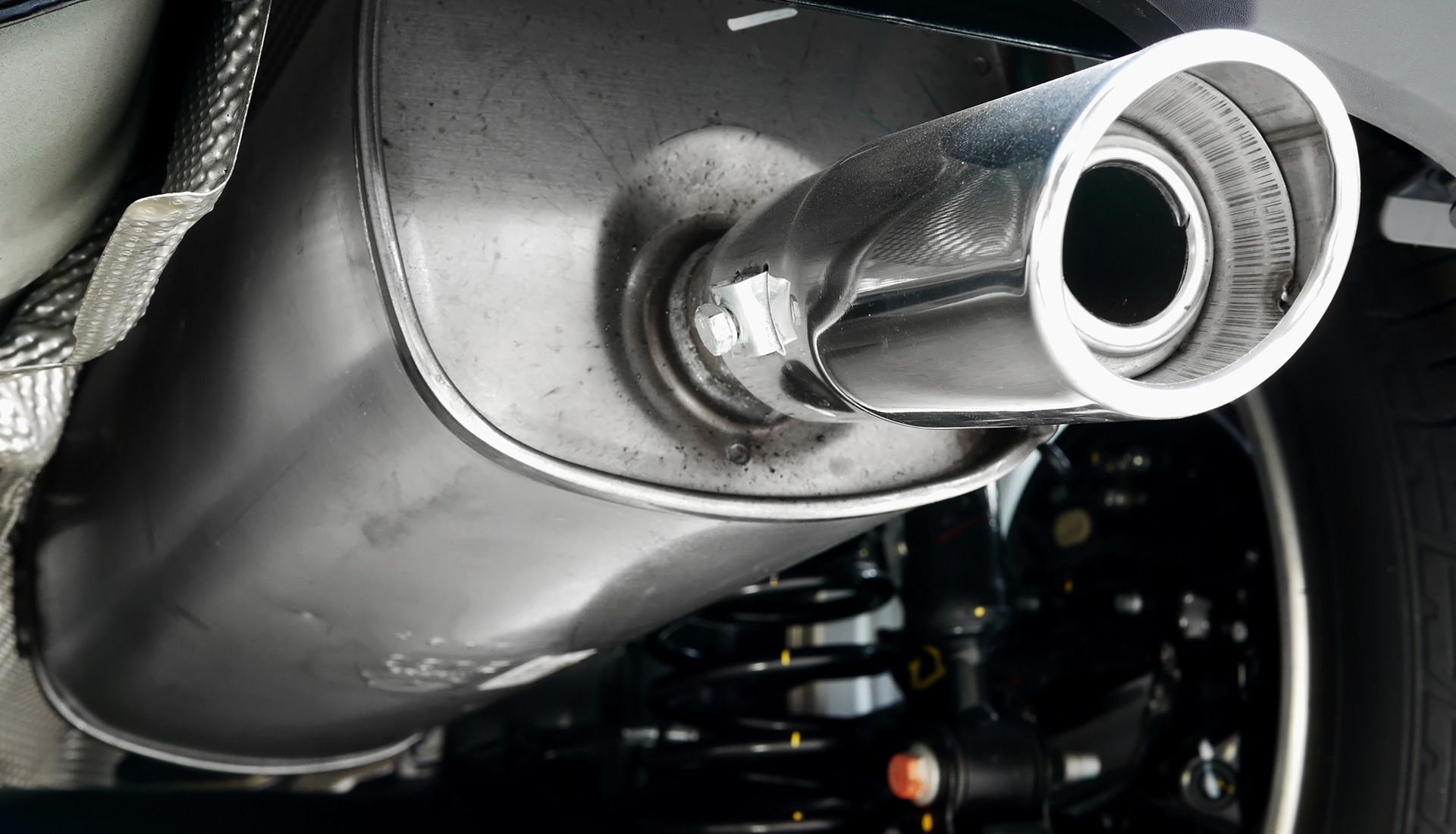 Car exhaust pipe and muffler. Chrome tip, dark metal, visible undercarriage.