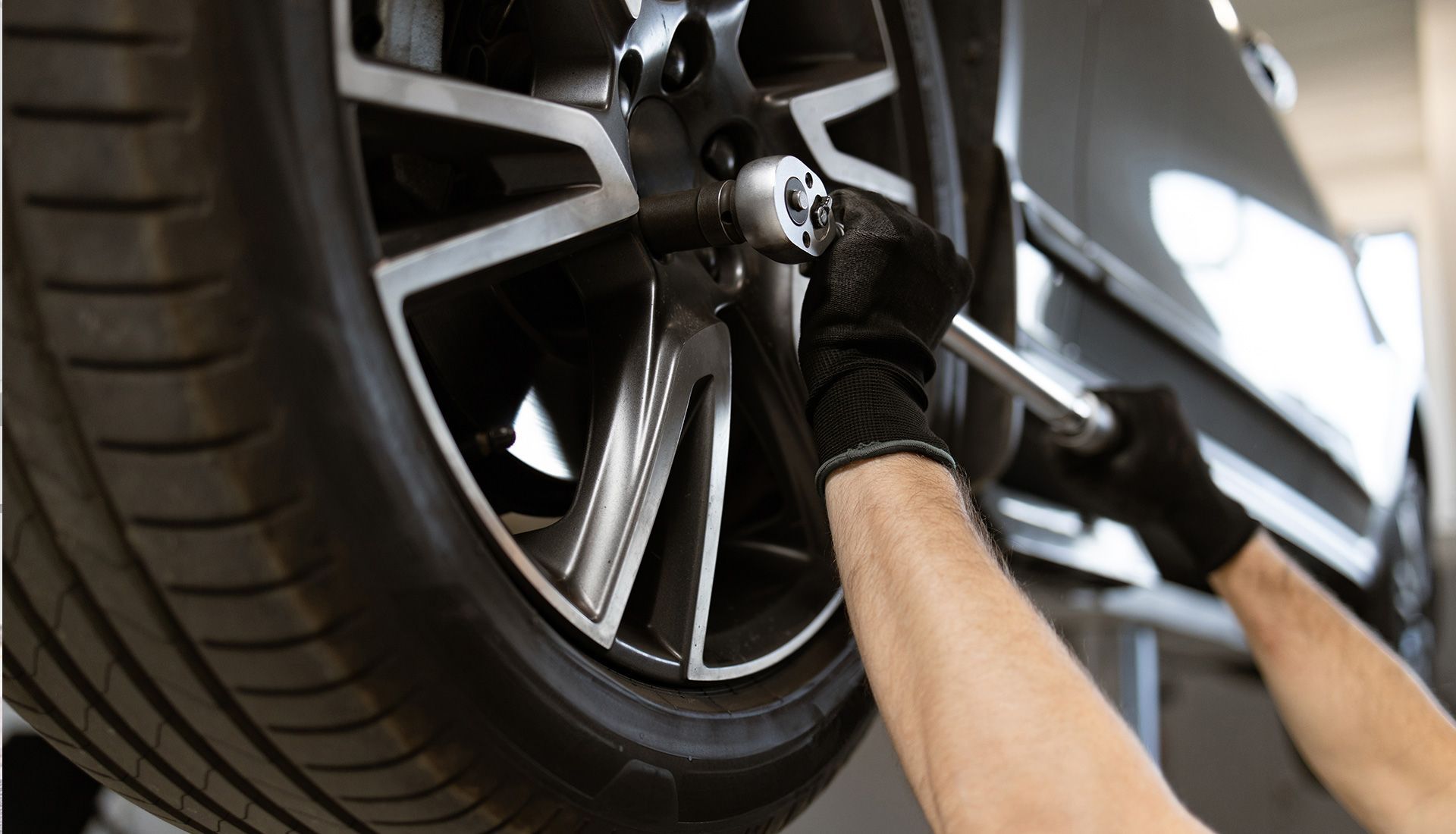 A mechanic using a wrench to remove lug nuts on a car tire.