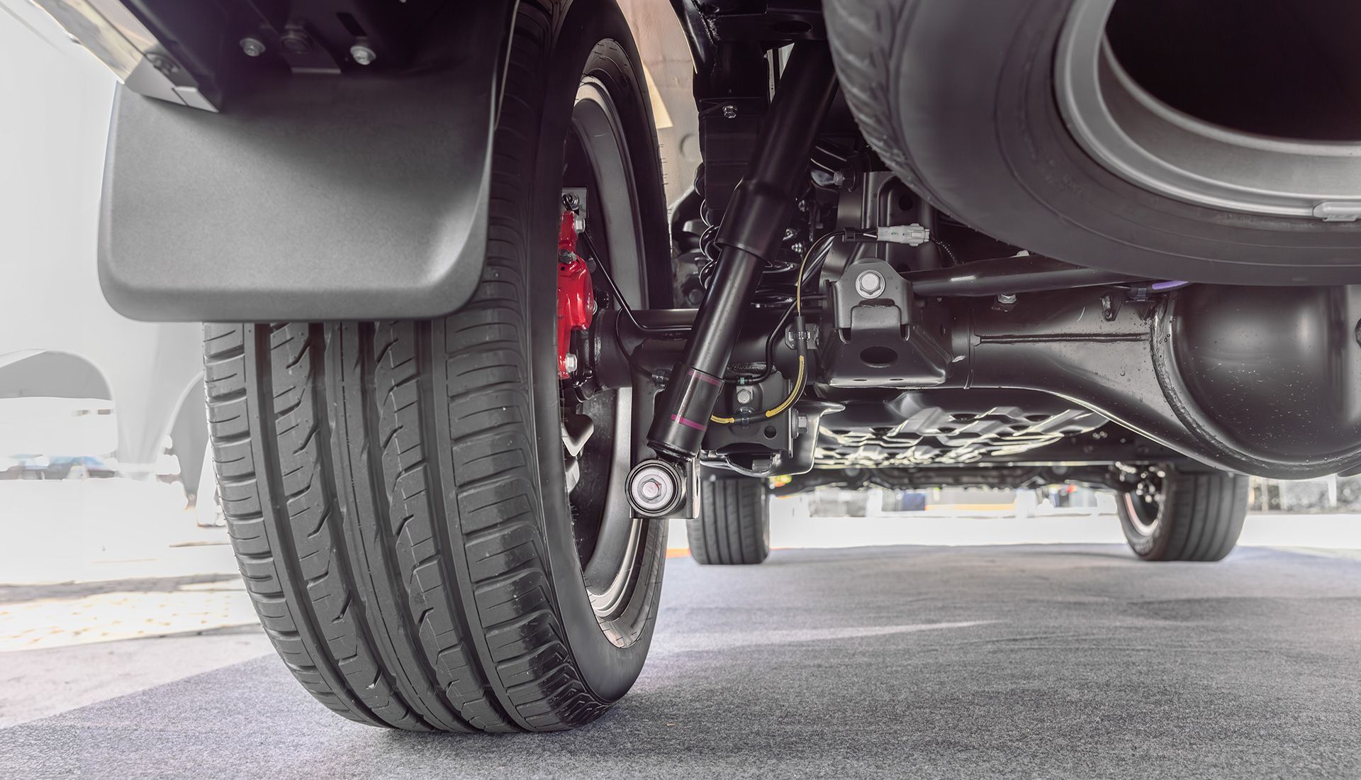 Rear undercarriage of a vehicle with a tire, suspension, and mud flap.