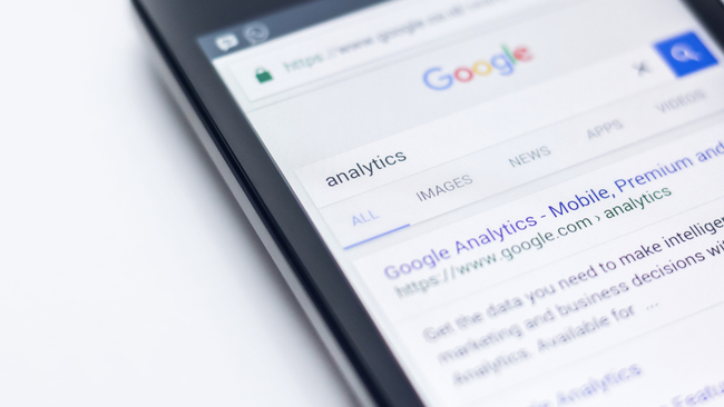 A close up of a cell phone displaying a google search page.