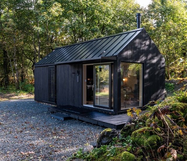 Black modern cabin in dappled morning light.