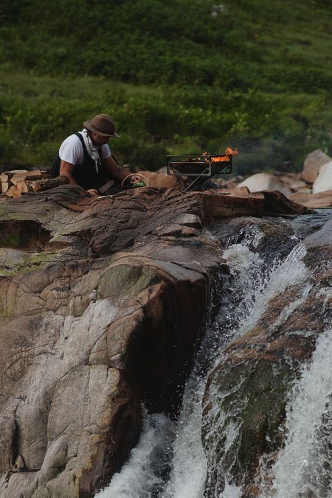 Chef William Hamer cooking next to a stream