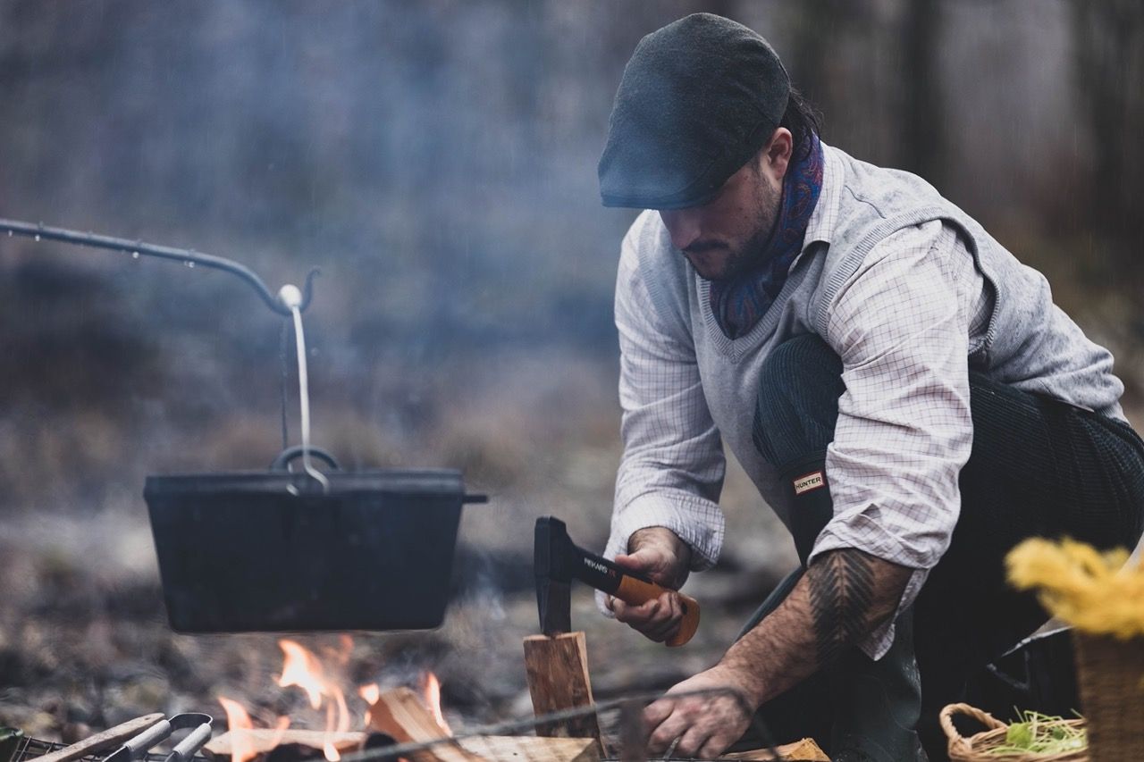 chef cooking over fire cast iron pot