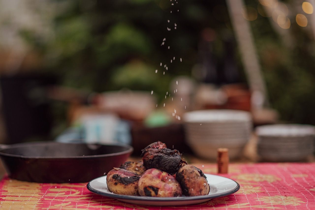 Salt being sprinkled on wild cooked potatoes.