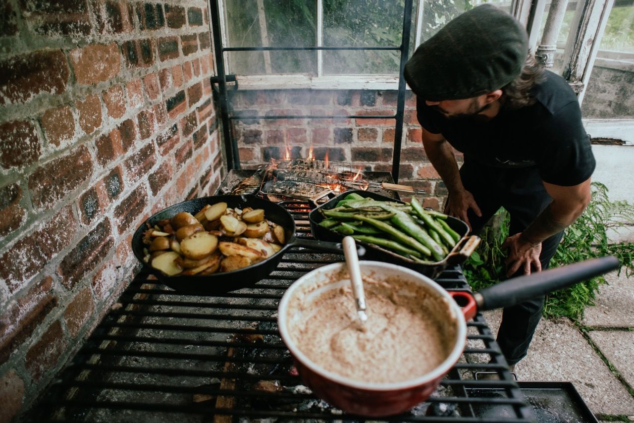 Chef william hamer cooking food over a fire.