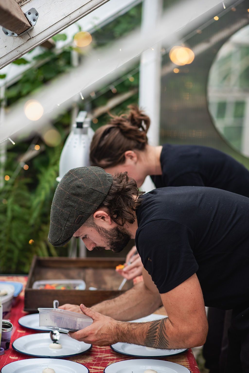 Chef and assistant plating up food in greenhouse.