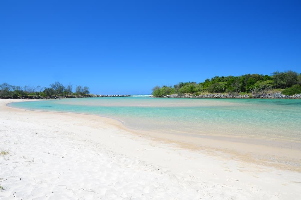 A White Sandy Beach With A Body Of Water In The Background — Byron Coast Removals In Pottsville, NSW