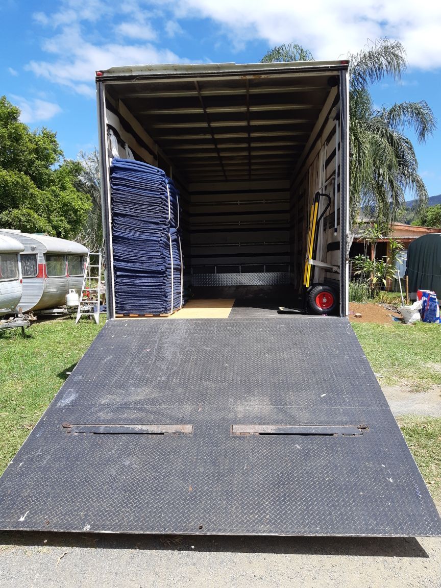 A Removalist Truck Is On The Road With The Back Open Loading Furniture — Byron Coast Removals In Main Arm, NSW