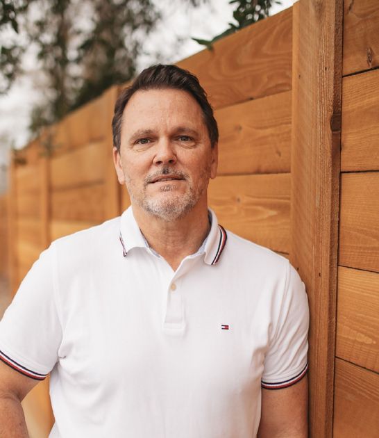 A woman is sitting at a desk with a laptop and a vase of flowers.