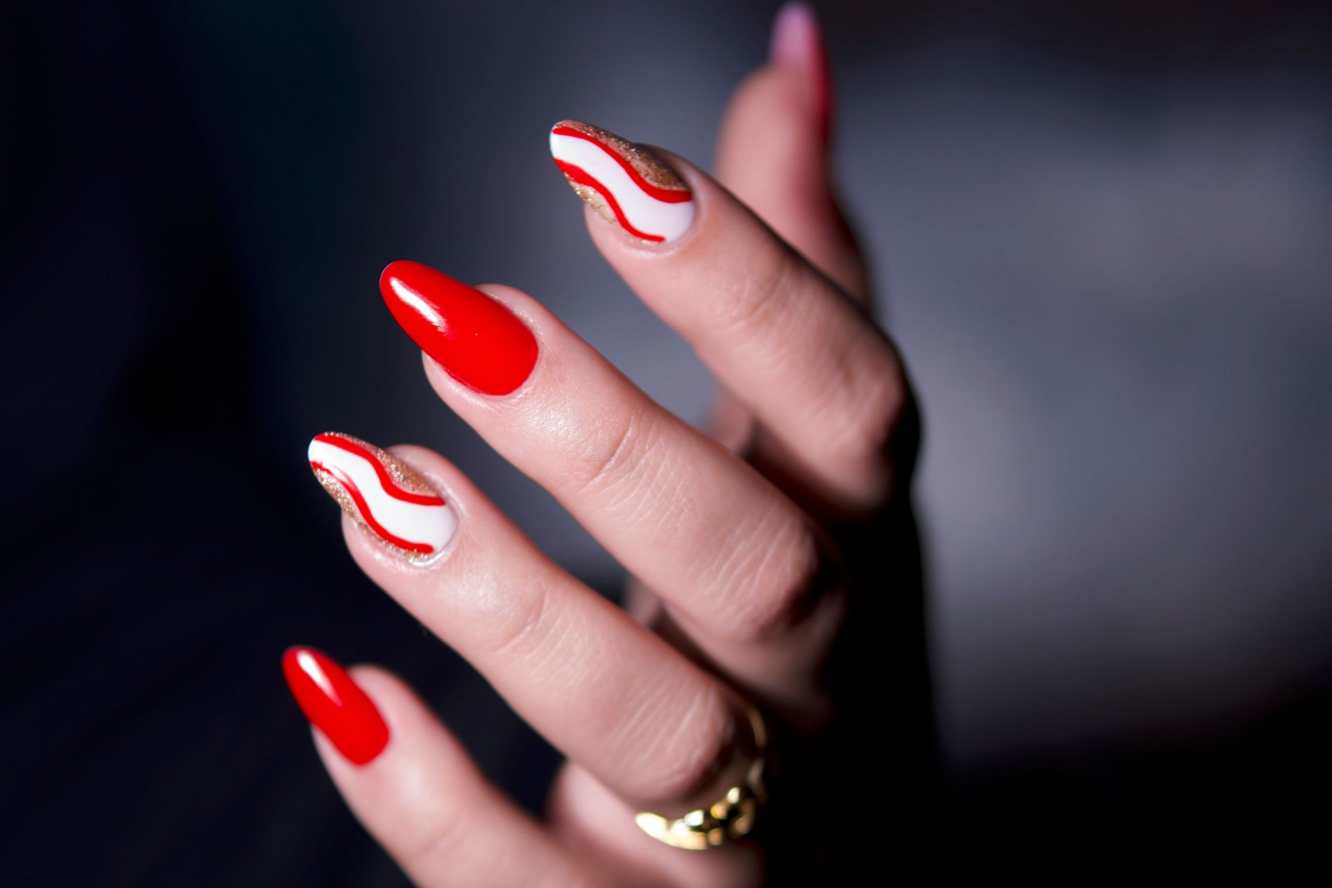 Professional manicure featuring red nail polish and decorative nail art on almond-shaped nails.