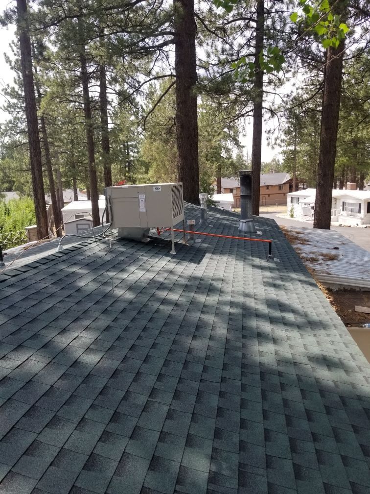 A roof with a box on top of it surrounded by trees.