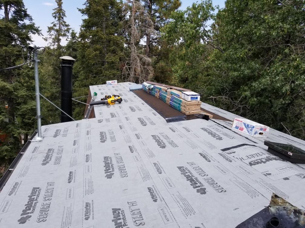 The roof of a house is being covered with a roofing material.