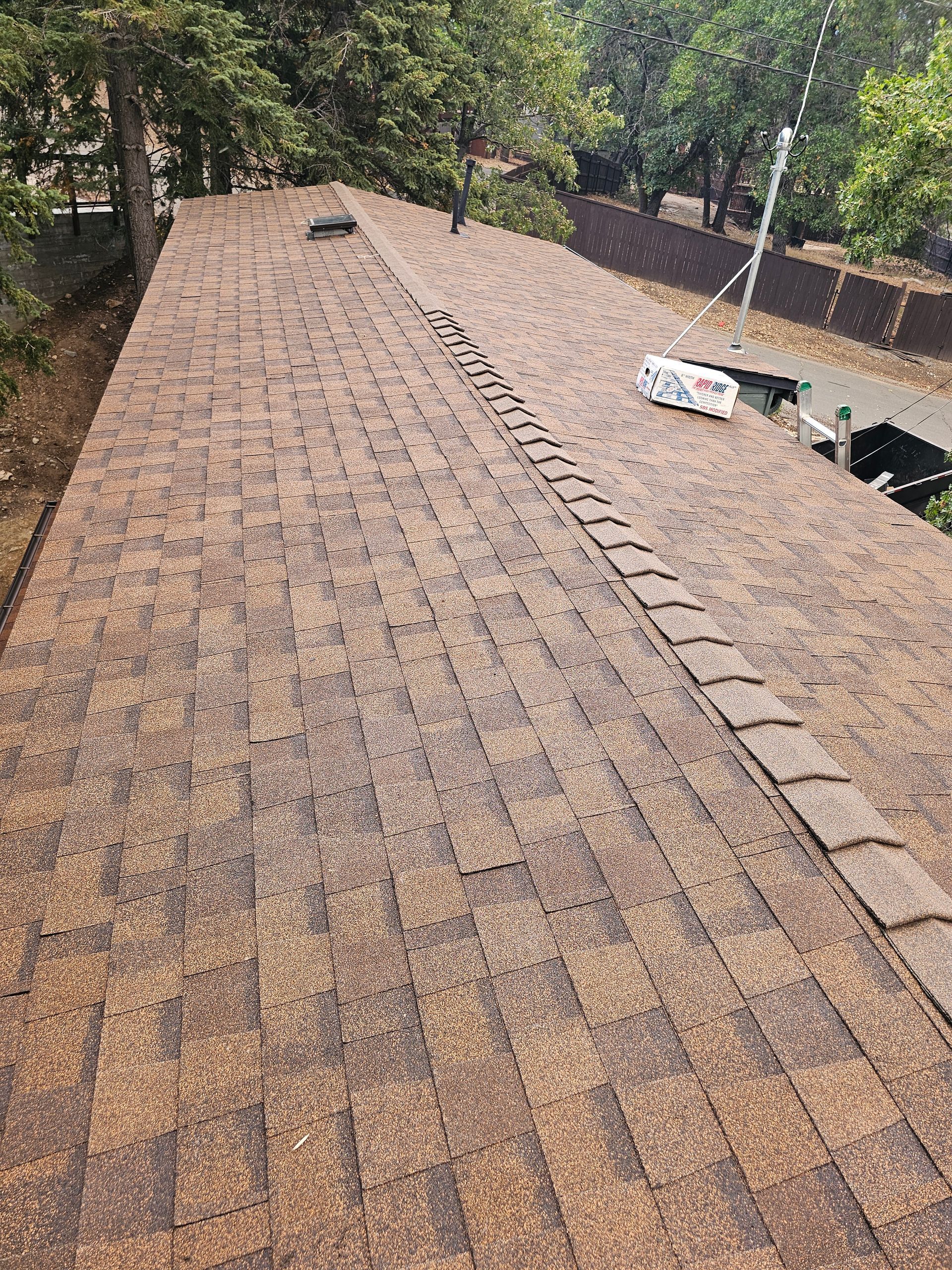 A roof with a lot of shingles on it and trees in the background.