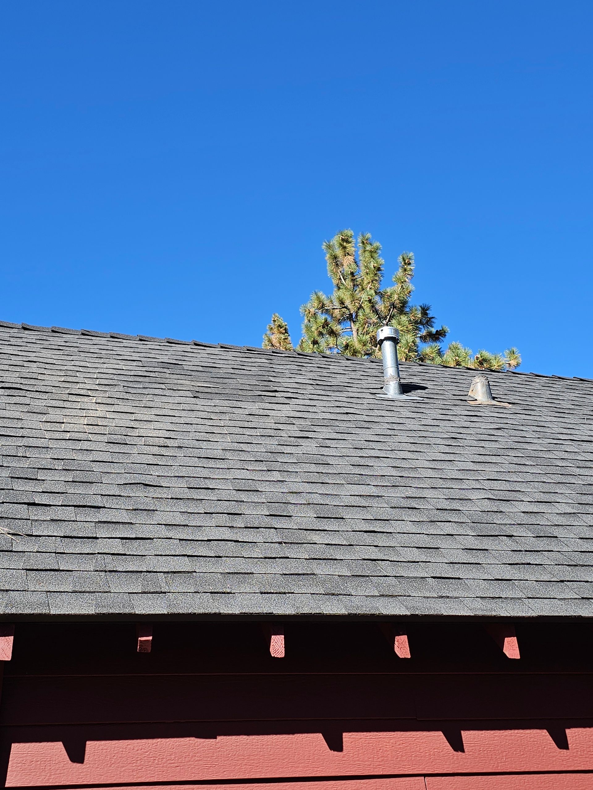 A roof with a chimney on it and a tree in the background