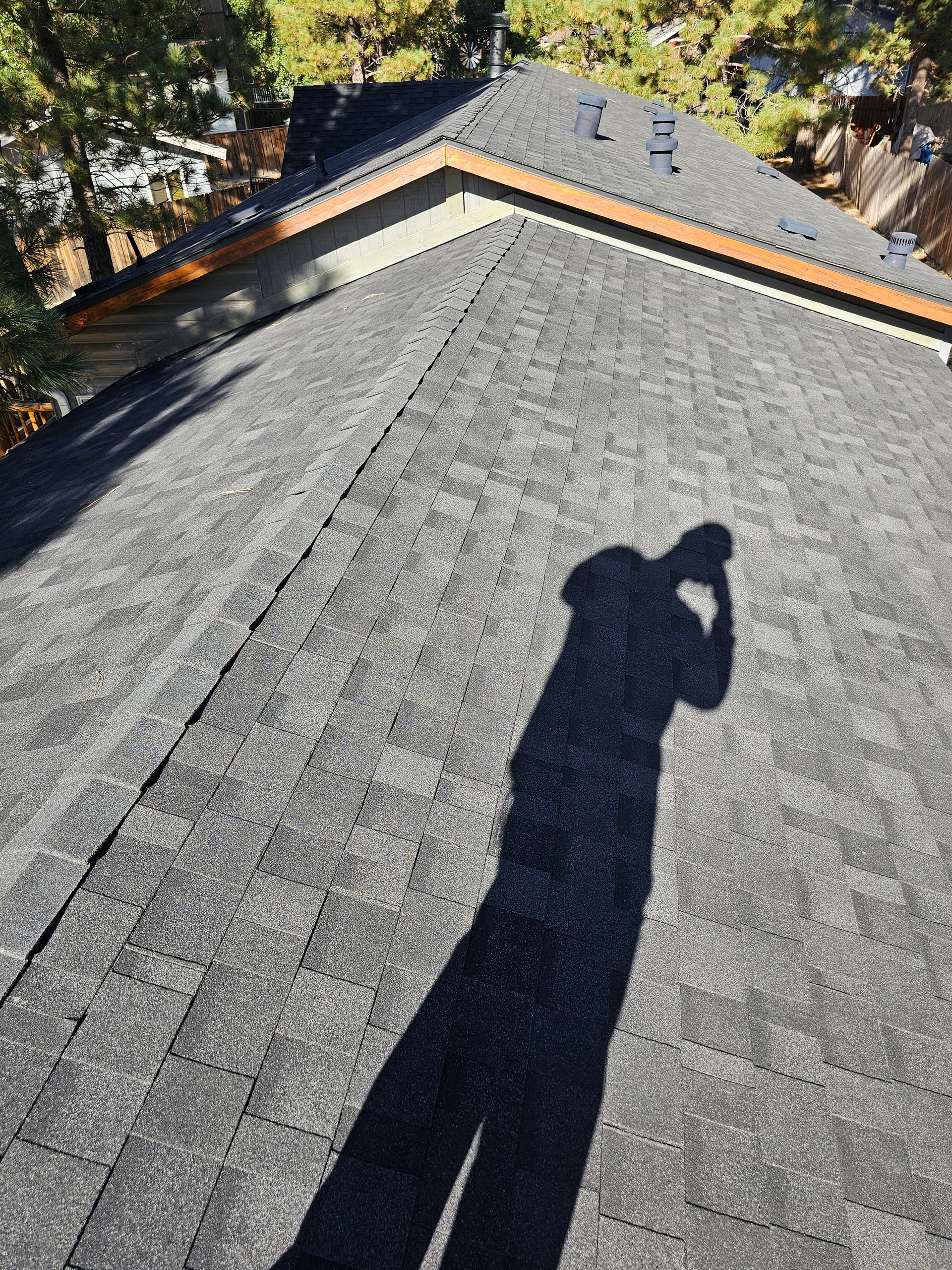 A shadow of a person is cast on the roof of a house.