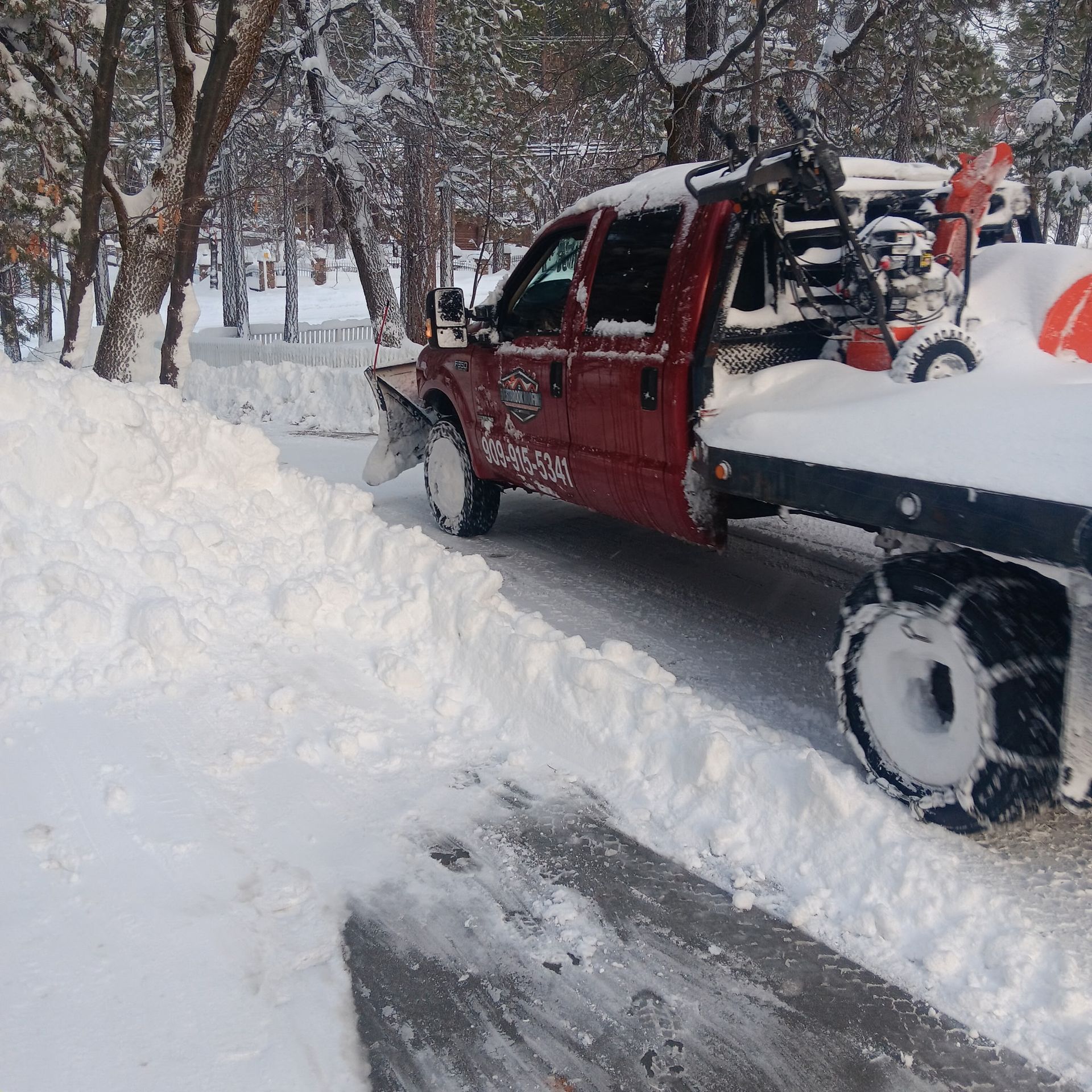 A red truck is driving down a snowy road
