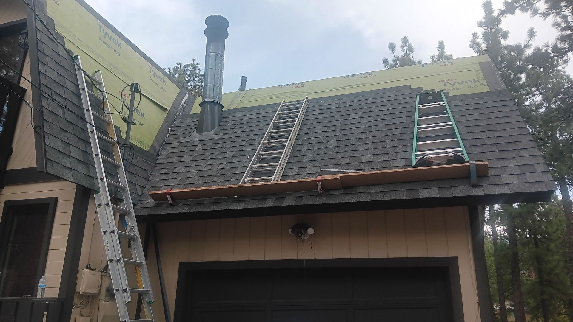 A ladder is sitting on top of a roof next to a garage.
