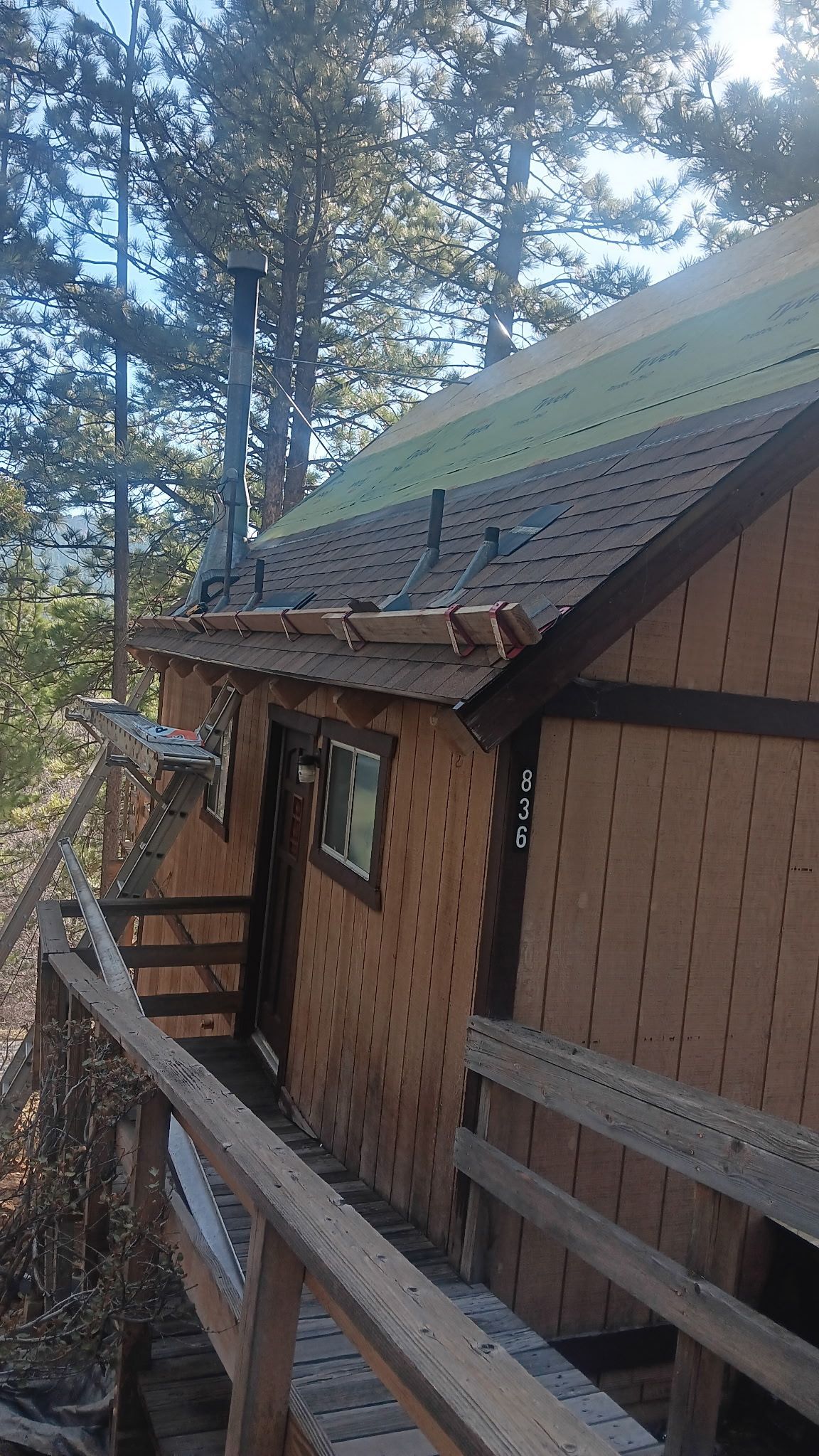 A wooden house with a roof that is covered in shingles is surrounded by trees.