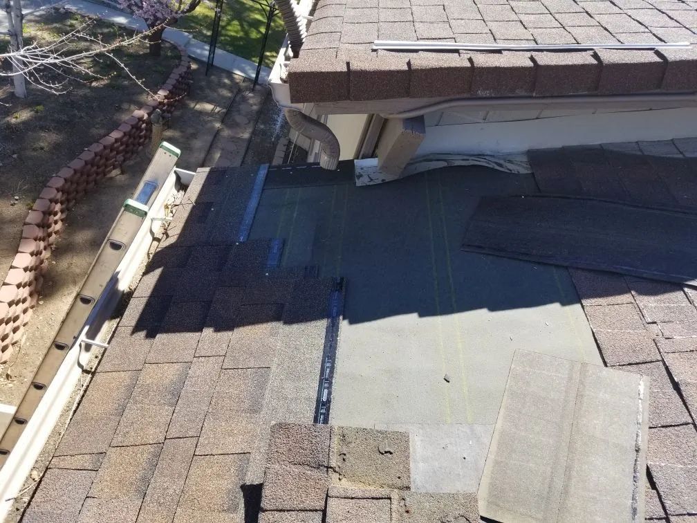 A roof with shingles missing and a gutter on it.