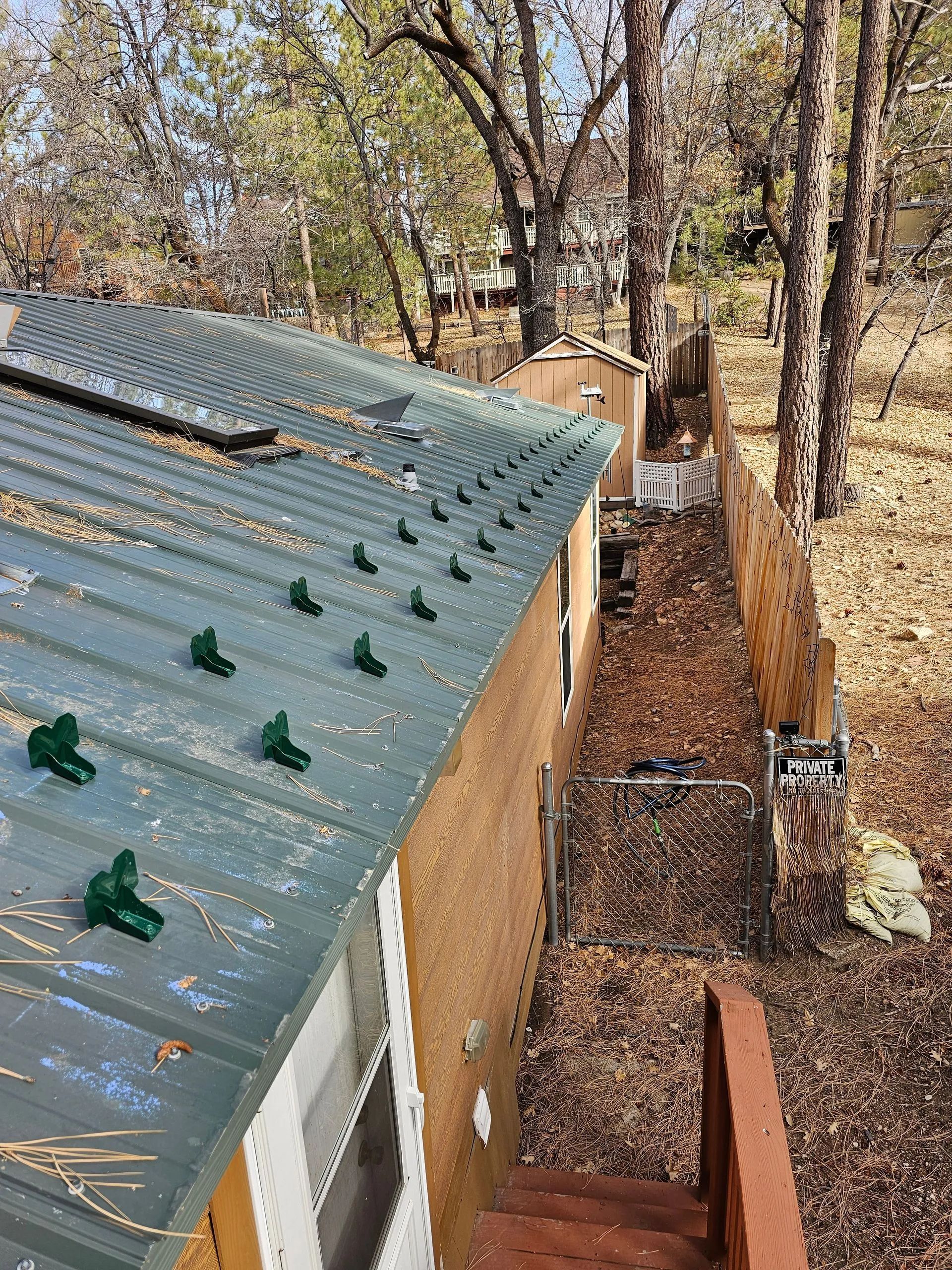 An aerial view of a house with a metal roof and snow anchors on it.