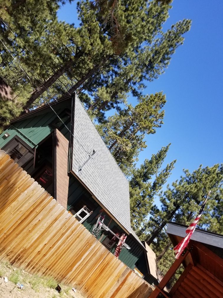A wooden fence surrounds a house in the woods.