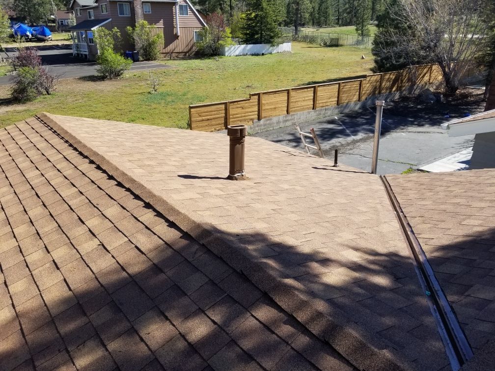 A roof with a chimney on it and a fence in the background.