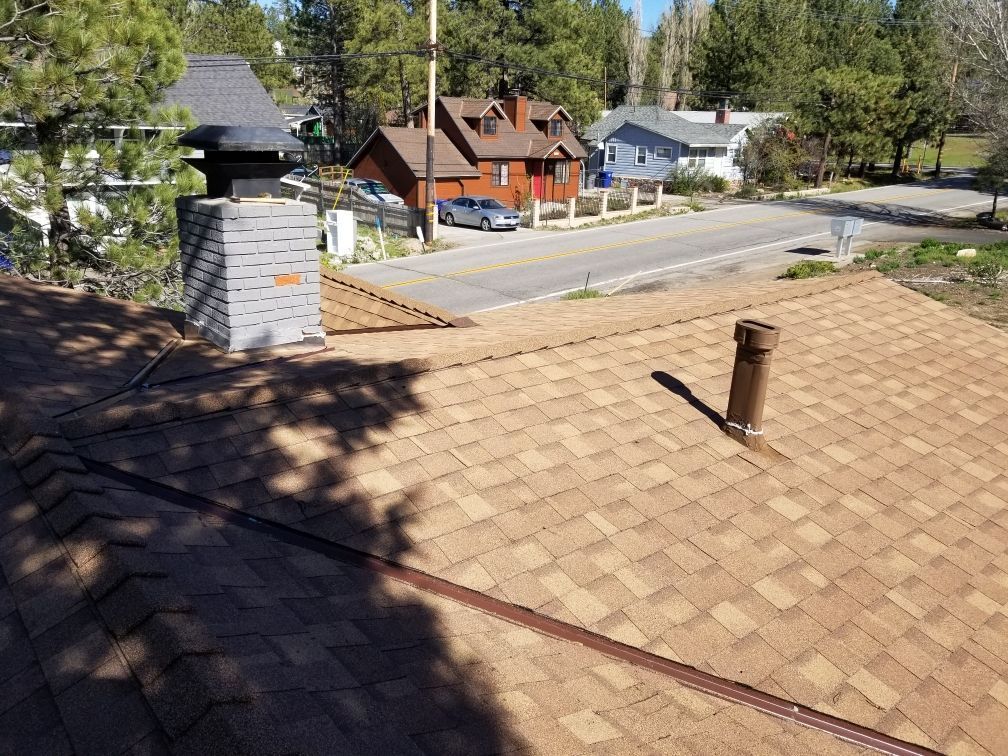 A roof with a chimney on it and a street in the background.