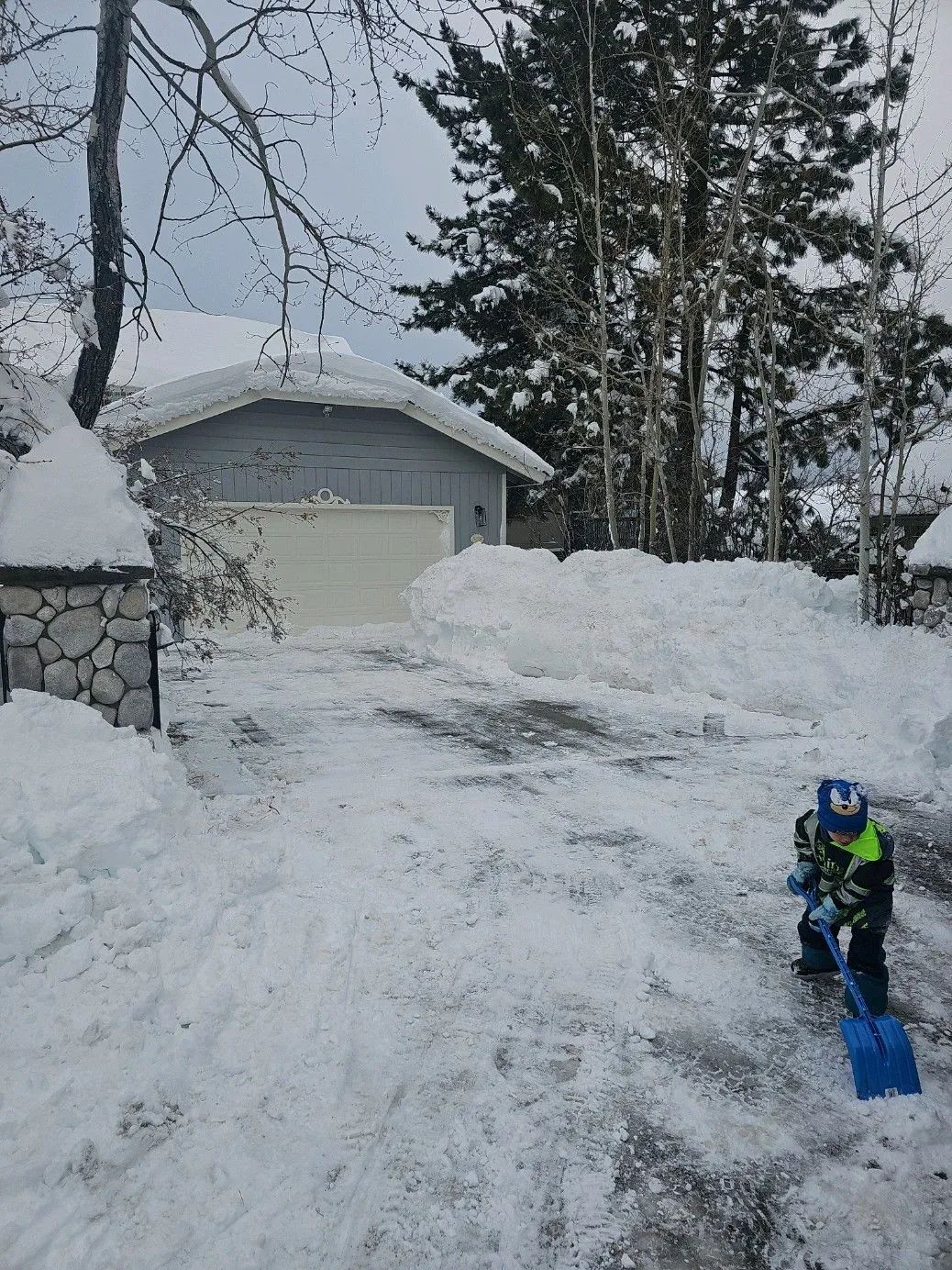 A person is shoveling snow from a driveway in front of a garage.