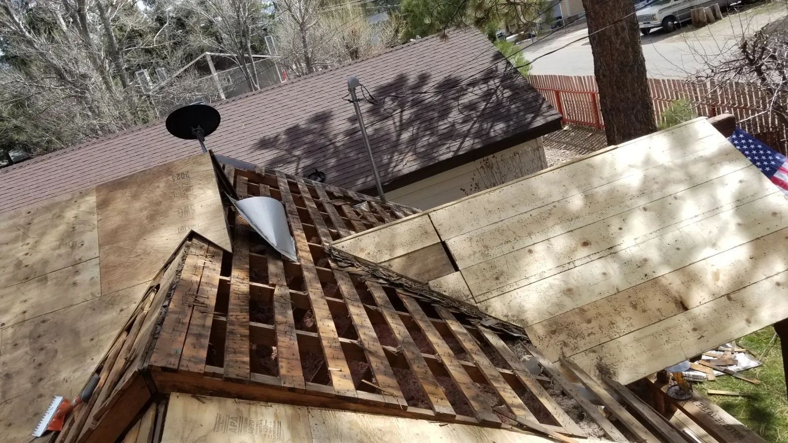The roof of a house is being repaired with wooden boards.
