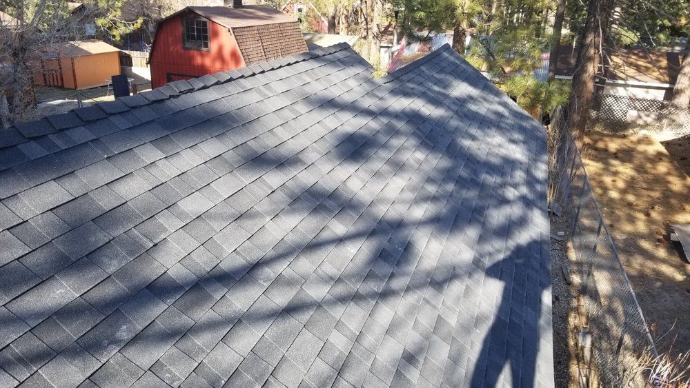 An aerial view of a roof with a red barn in the background.