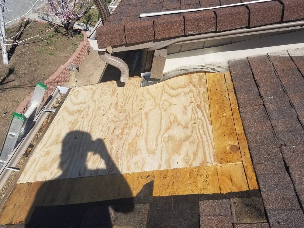 A person is taking a picture of a piece of plywood on a roof.