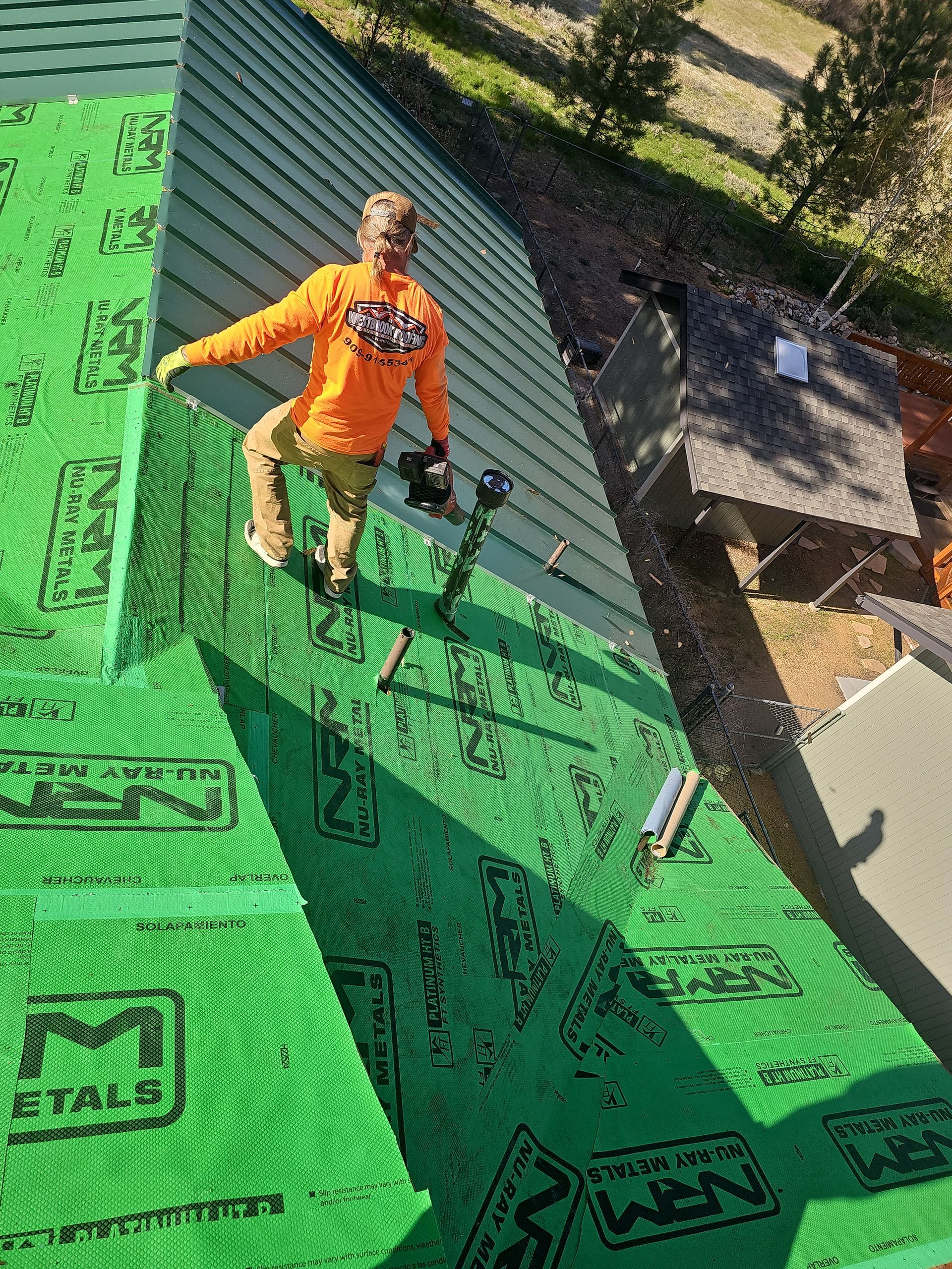 A man is standing on top of a green roof.