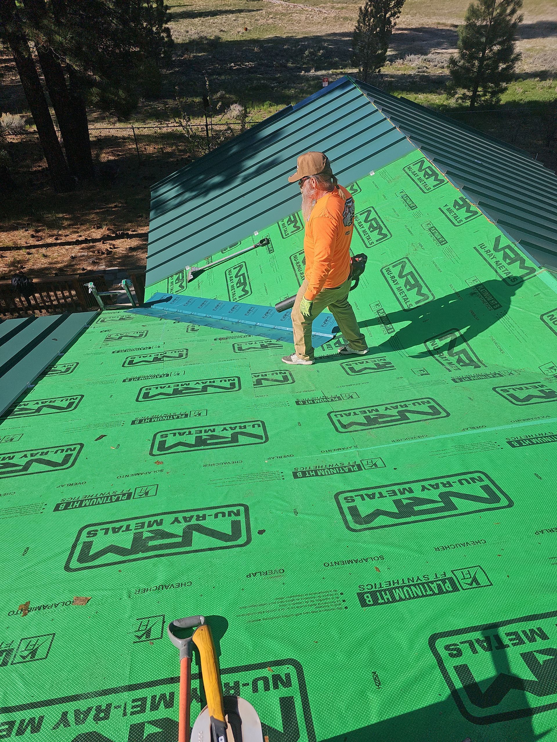 A man is standing on top of a green roof.