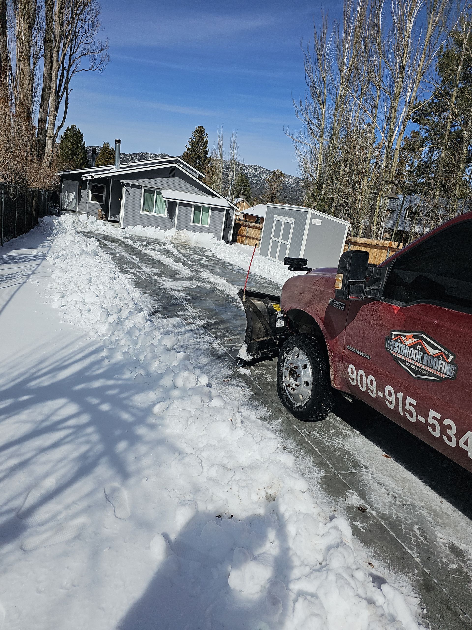 A snow plow is parked on the side of a snow covered road.