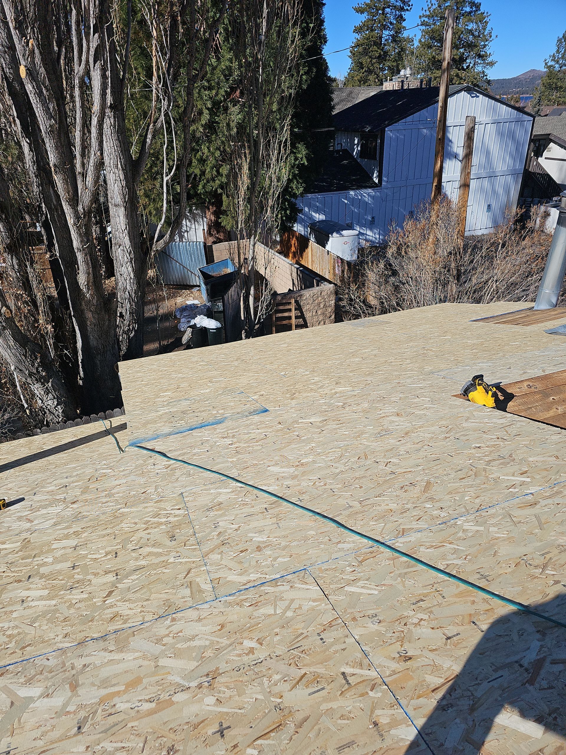 A man is standing on top of a pile of plywood in front of a house.