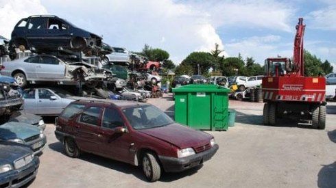 Un'auto rossa è parcheggiata davanti a una pila di auto