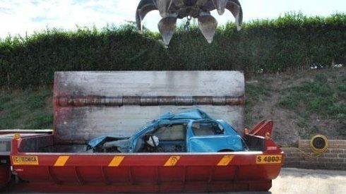 Un'auto blu viene sollevata da un cassonetto